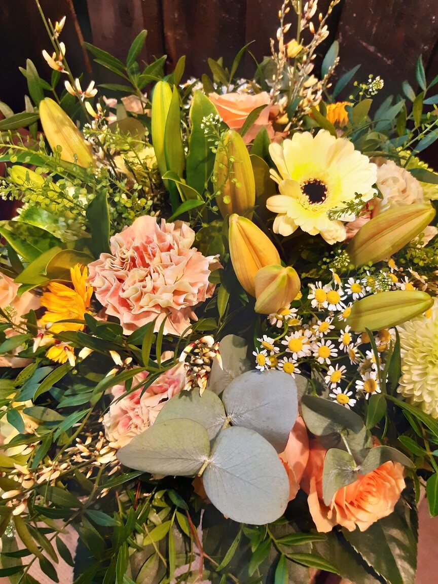 Ein bunter Blumenstrauß mit Rosen, Lilien und Gänseblümchen in voller Blüte