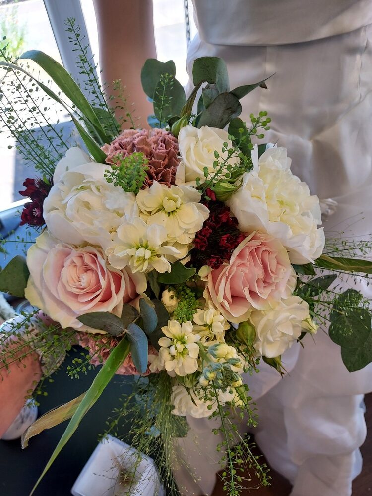 Ein bunter Blumenstrauß aus Rosen, Nelken und Grün in sanften Pastelltönen
