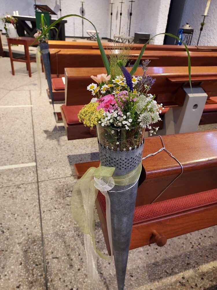 Blumenarrangement in einer Kirche mit bunten Blüten und rustikaler Vase