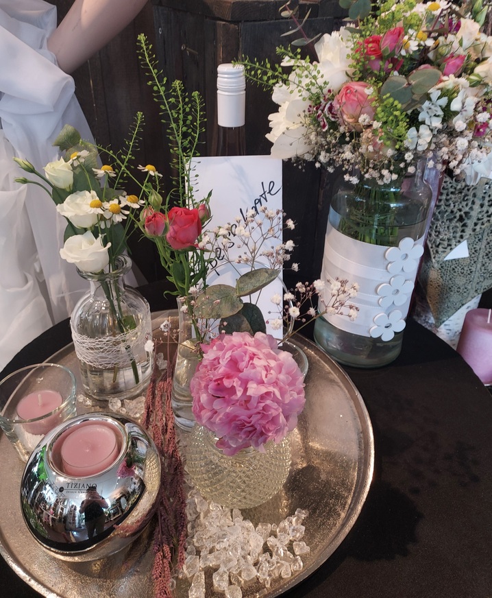 Verschiedene Blumen in Vasen auf einem Tisch, zart und farbenfroh arrangiert.