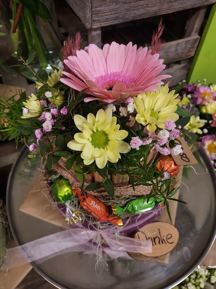 Ein bunter Blumenstrauß mit rosa und gelben Blüten auf einem rustikalen Tisch