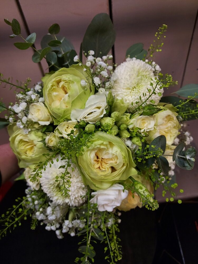 Ein kunstvoll gebundener Blumenstrauß mit weißen und grünen Blüten.