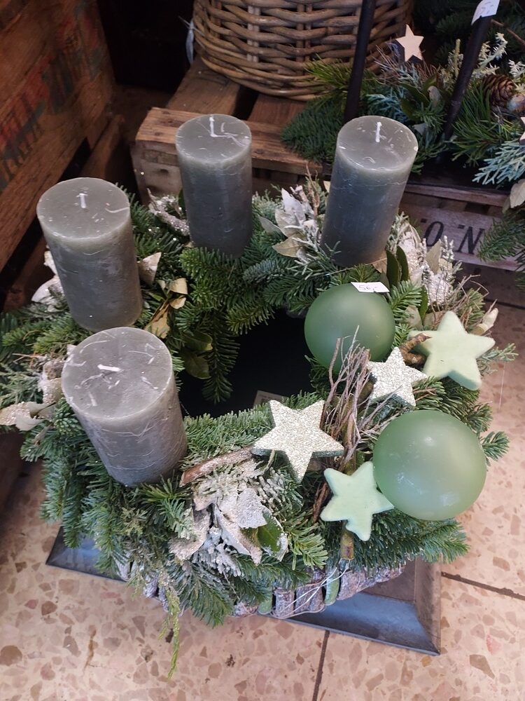 Grüner Adventskranz mit grauen Kerzen, weißen Sternen und grüne Kugeln.