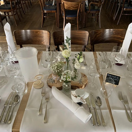 Elegant gedeckter Tisch mit weißen Servietten, Gläsern und Blumenarrangement