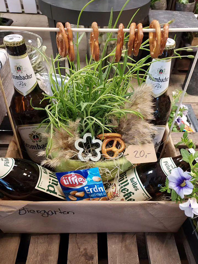 Eine rustikale Geschenkbox mit Bierflaschen, Brezeln und Grasdeko.