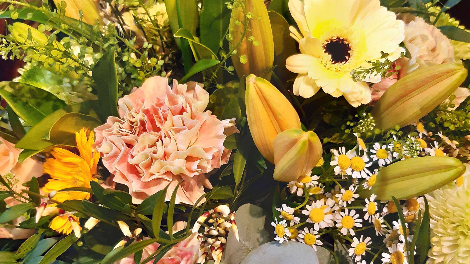 Ein bunter Blumenstrauß mit gelben Lilien und rosa Nelken in voller Blüte