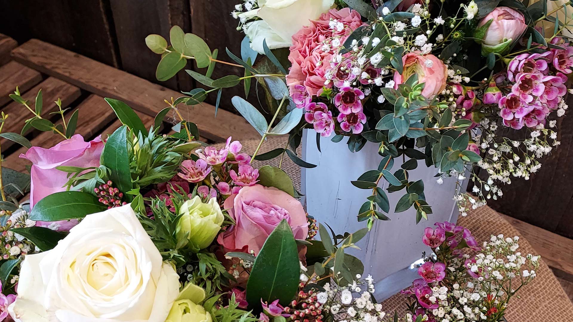 Bunte Blumengestecke mit Rosen, Schleierkraut und Eukalyptus in Vasen.
