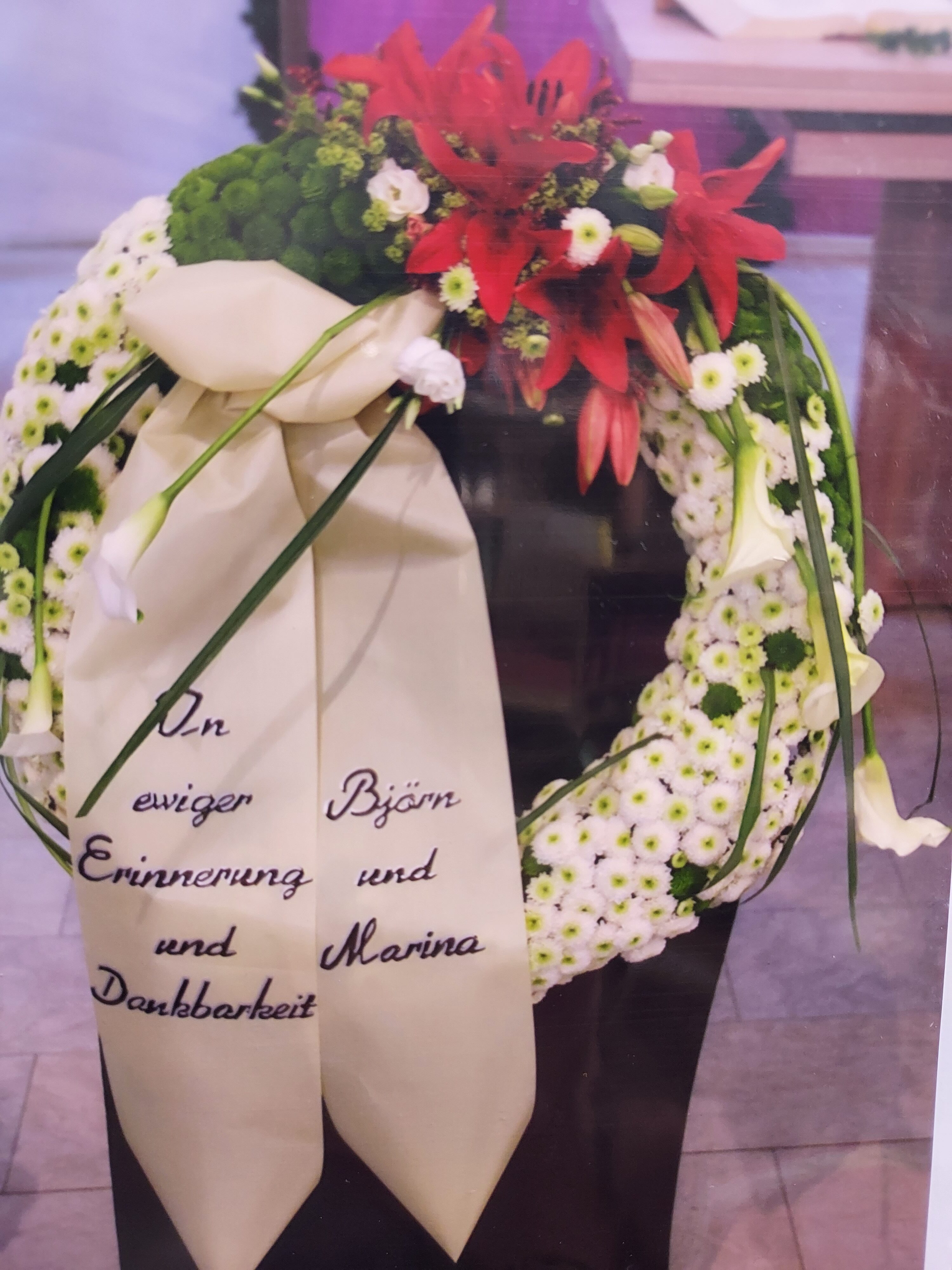 Bestattungs­kranz mit weißen und roten Blumen sowie Schleife mit Widmung