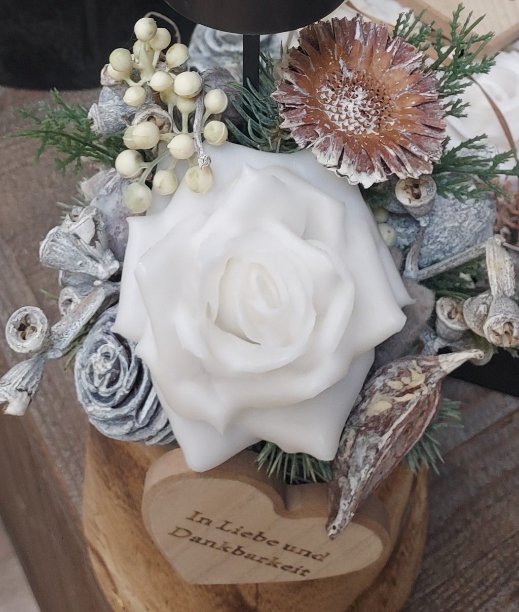 Weiße Rose aus Wachs mit Trockenblumen auf Holz mit herzförmigem Schriftzug