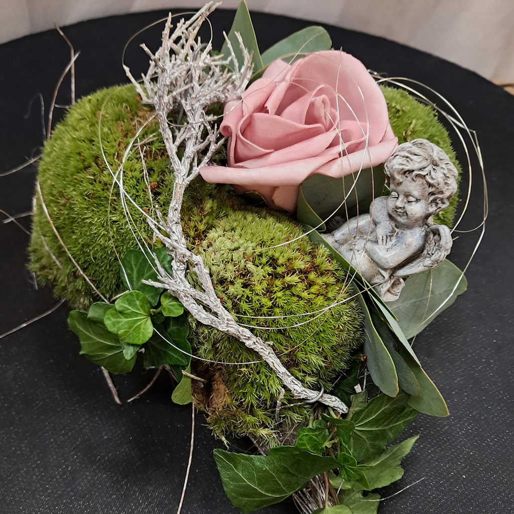 Rosa Rose und Moos in Herzform mit silbernem Zweig und Engelsfigur dekoriert
